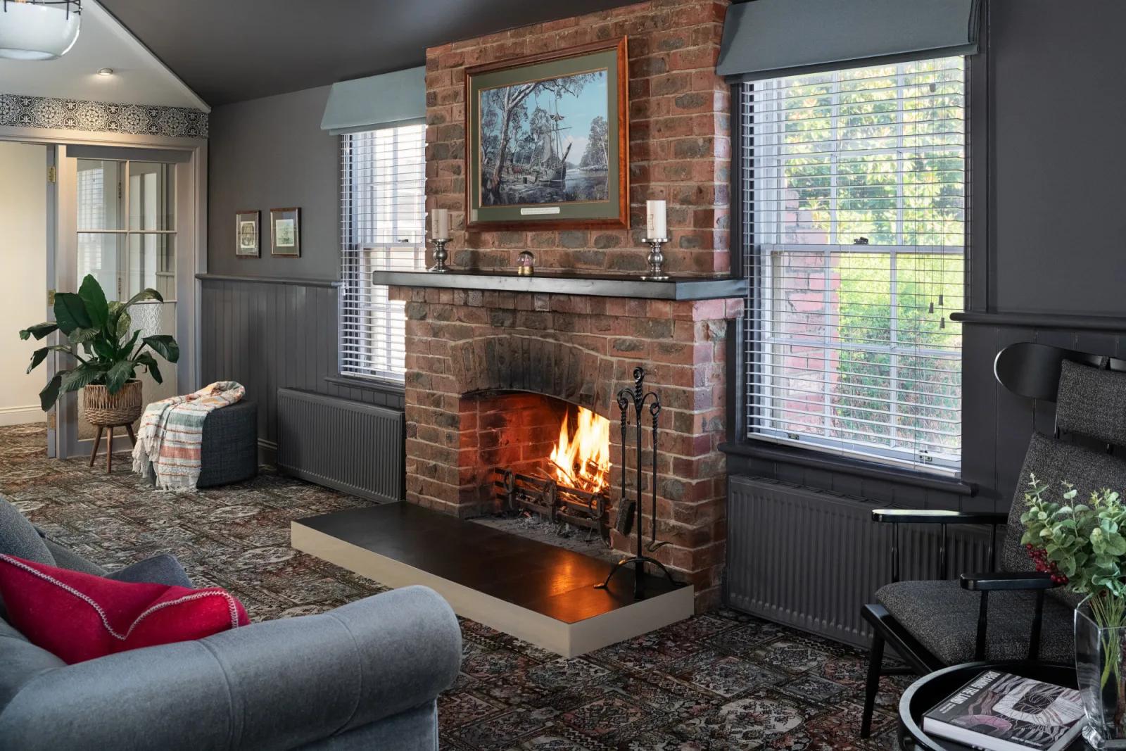 Warm heritage lounge room with fireplace, armchairs, and historic décor, from Australia’s most visited outdoor museum and heritage attraction.