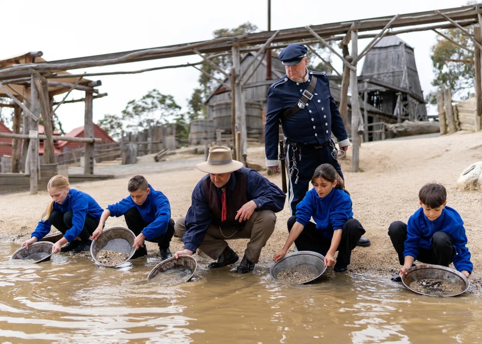 School students panning for gold with a costumed educator and police officer at Sovereign Hill’s historic gold diggings.