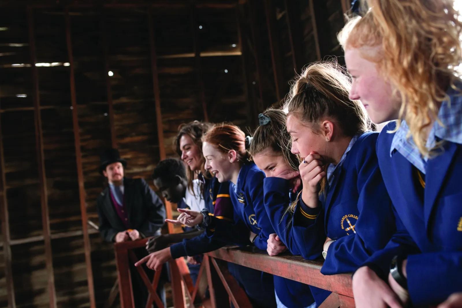 School students in uniform listening to a costumed educator during an interactive learning experience at Sovereign Hill.