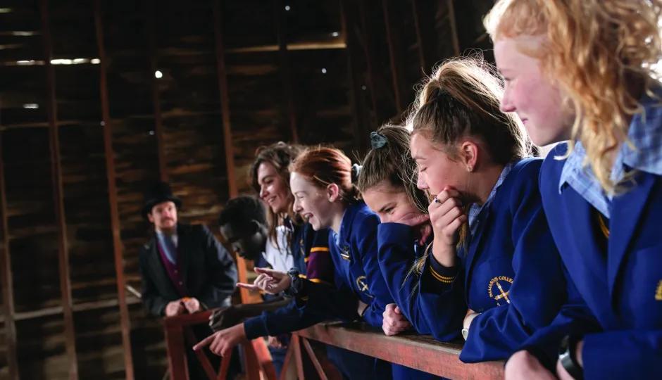 School students in uniform listening to a costumed educator during an interactive learning experience at Sovereign Hill.