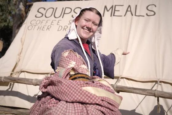 Costumed woman reenactor smiling outside goldfields soup and meals tent, from Australia’s most visited outdoor museum and heritage attraction.