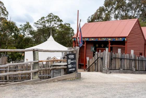 Chinese Camp entrance at Sovereign Hill featuring a red timber building, canvas tent and interpretive signage about Chinese migrants on the goldfields.