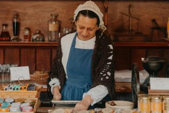 Costumed apothecary demonstrating traditional pill rolling with historical pharmacy tools inside Sovereign Hill’s apothecary.